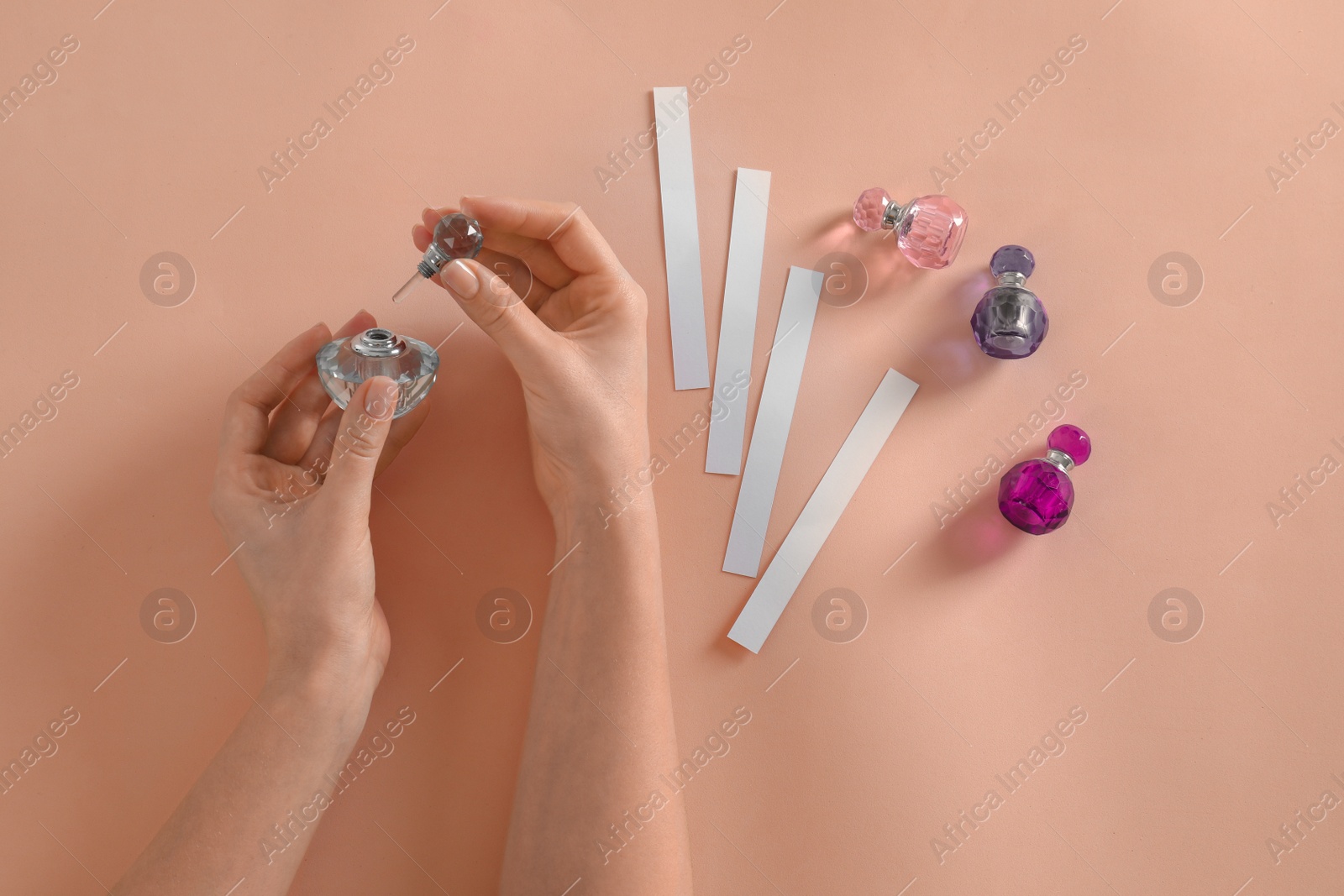 Photo of Woman with bottle of perfume on peach background, top view