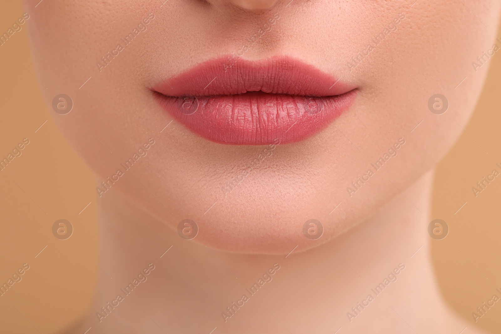 Photo of Young woman with beautiful full lips on beige background, closeup