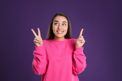 Photo of Woman showing number three with her hands on purple background