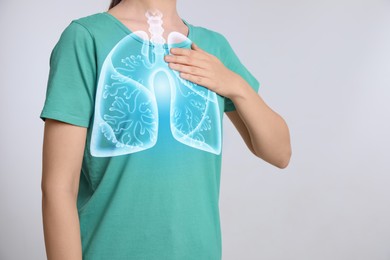 Woman holding hand near chest with illustration of lungs on light grey background, closeup