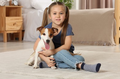 Cute girl with her dog on floor at home. Adorable pet