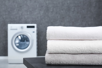 Stack of clean towels on table in laundry room, closeup. Space for text