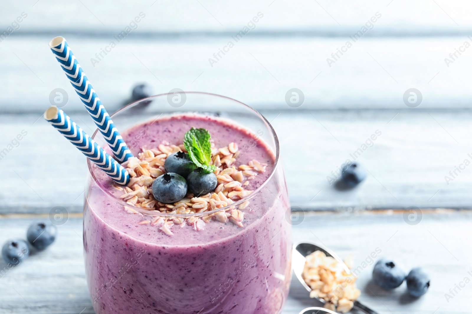 Photo of Tasty blueberry smoothie with oatmeal and berries in glass on table, closeup