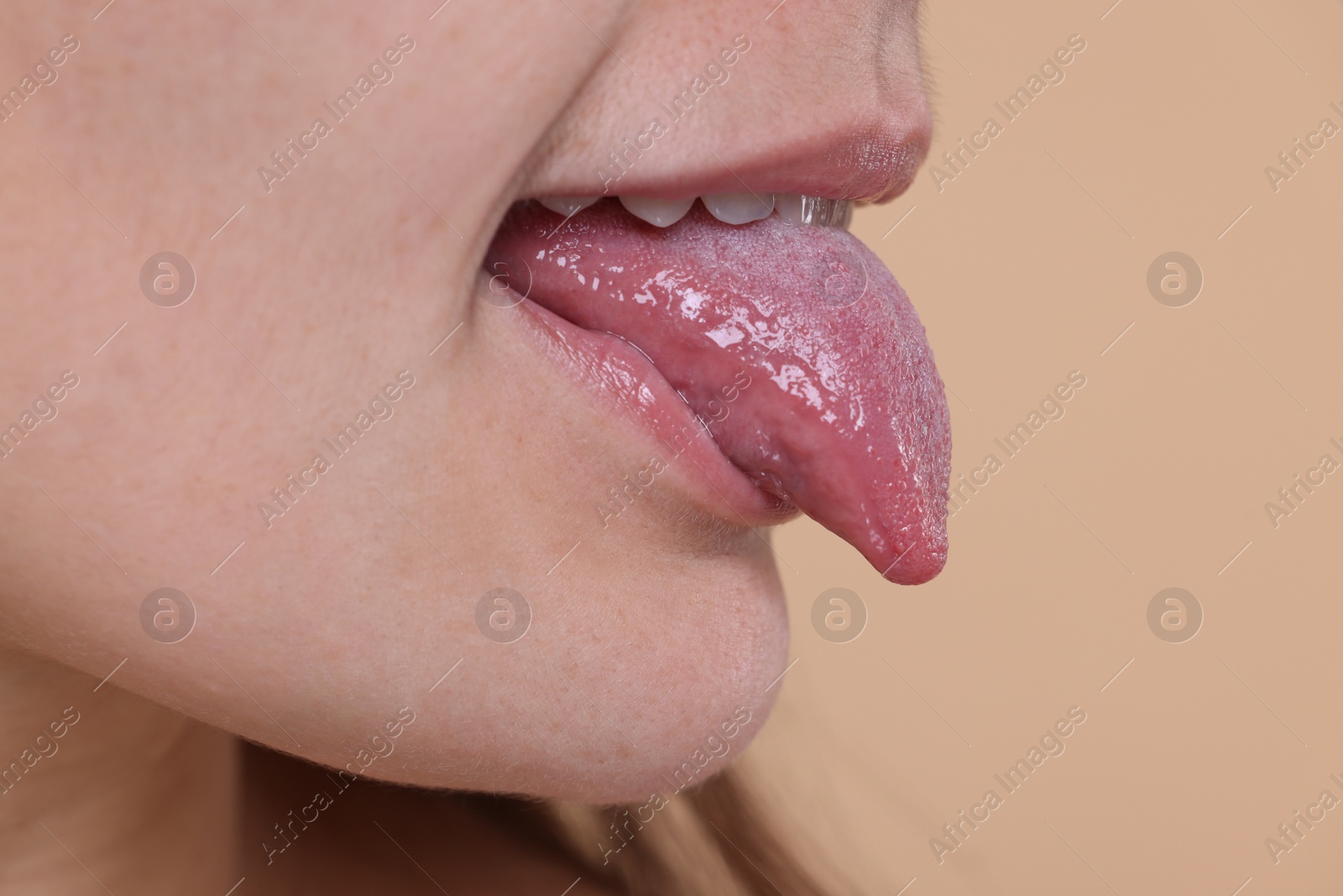 Photo of Woman showing her tongue on beige background, closeup. Space for text