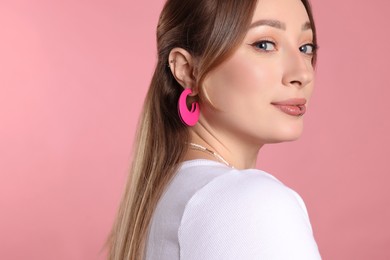 Photo of Young woman with lip and ear piercings on pink background. Space for text