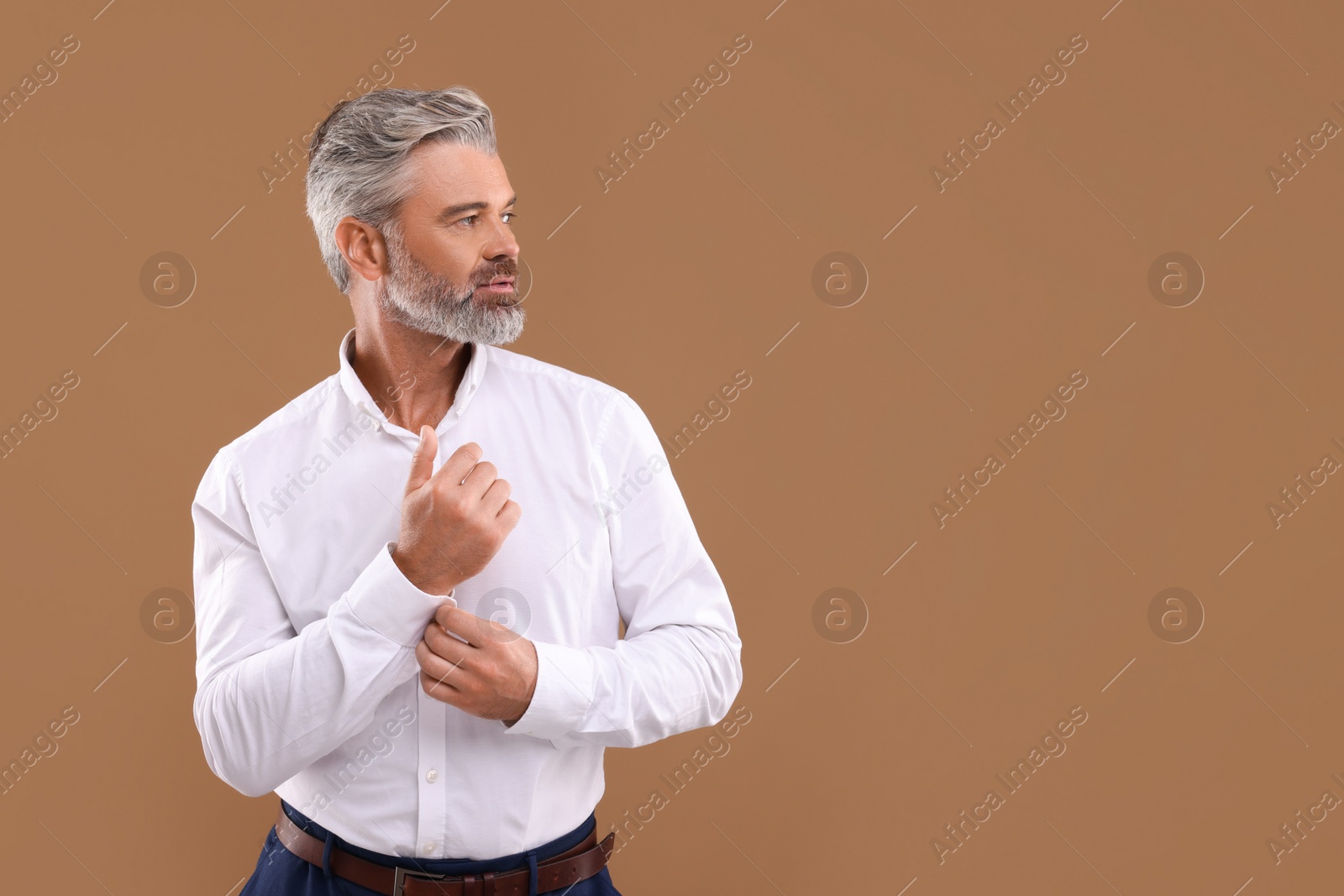 Photo of Portrait of confident man with beautiful hairstyle on light brown background. Space for text