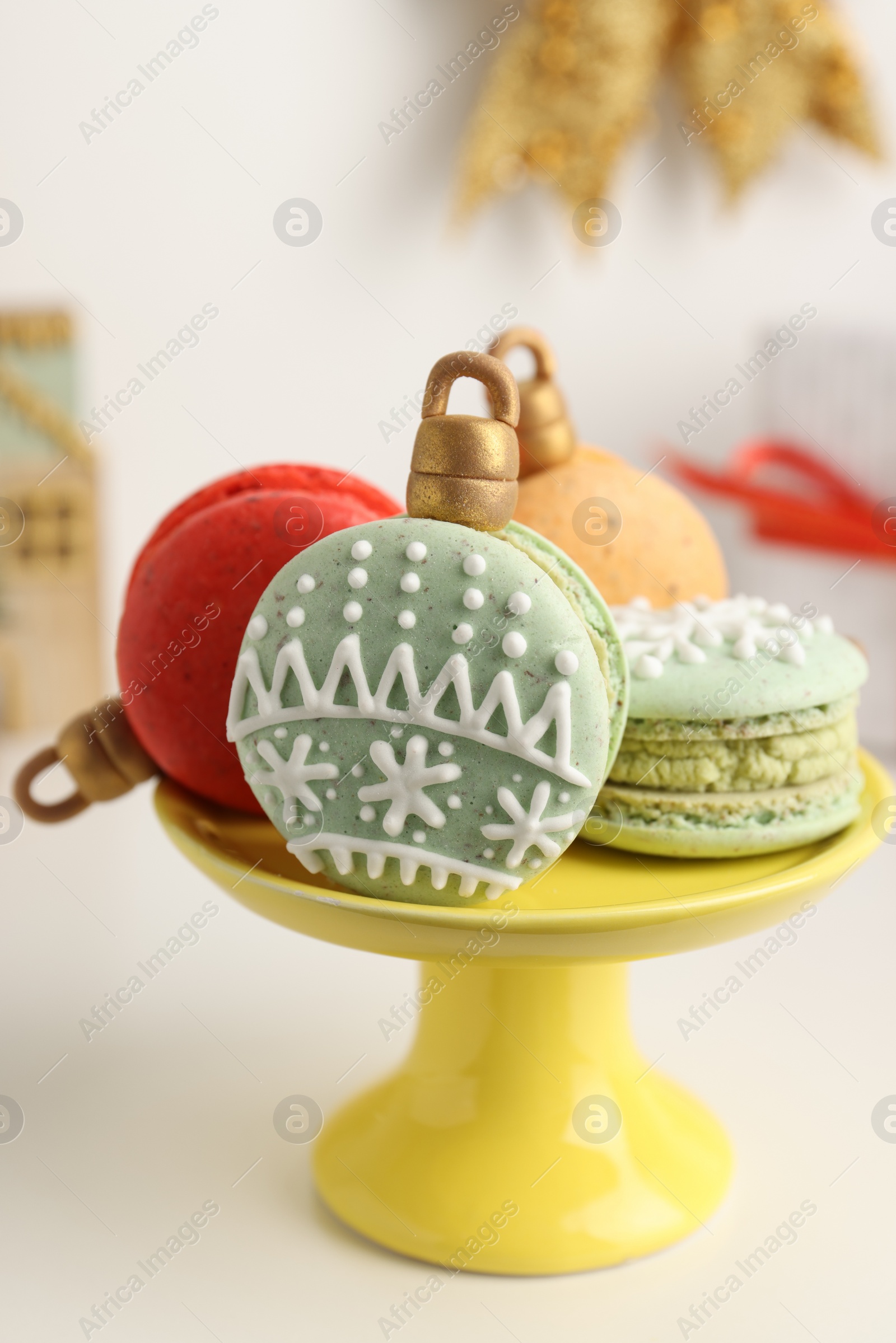 Photo of Stand with beautifully decorated Christmas macarons on white table