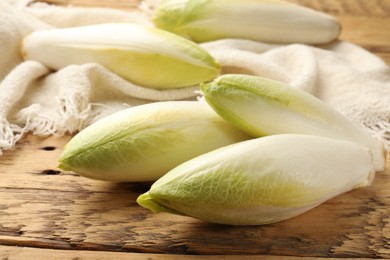 Photo of Fresh raw Belgian endives (chicory) on wooden table, closeup