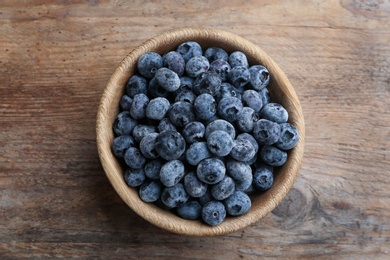 Photo of Tasty frozen blueberries on wooden table, top view