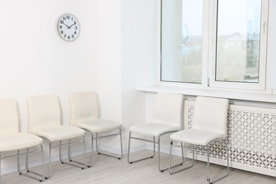 Many chairs near white wall in waiting area indoors