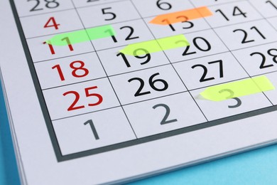 Photo of Timetable. Calendar page with colorful sticky notes on light blue background, closeup
