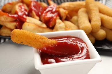Photo of Delicious cheese stick and ketchup in bowl on light grey table, closeup