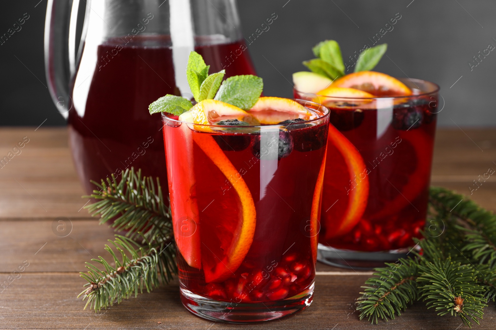 Photo of Aromatic Christmas Sangria drink and fir branches on wooden table