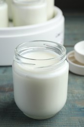 Photo of Glass jar with tasty yogurt on blue wooden table