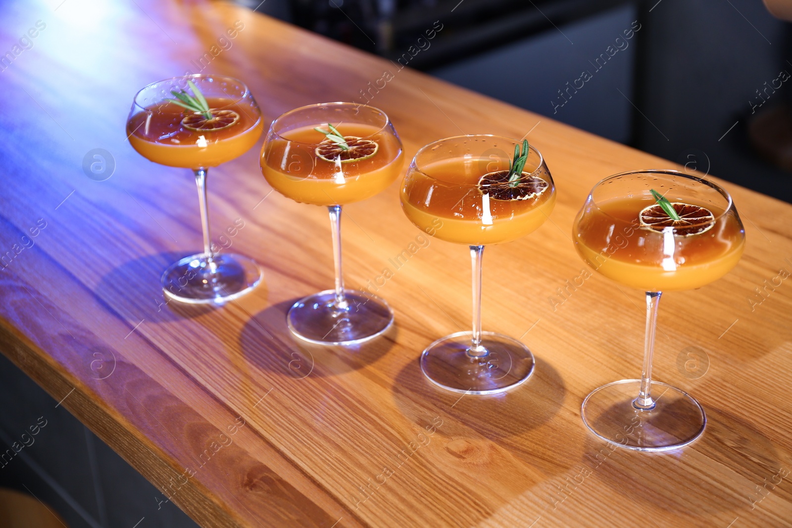 Photo of Glasses of delicious cocktail with vodka on wooden counter in bar