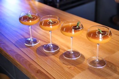 Glasses of delicious cocktail with vodka on wooden counter in bar