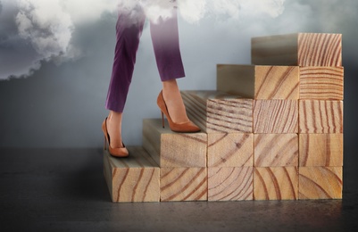 Businesswoman walking up stairs against grey background, closeup. Career ladder concept