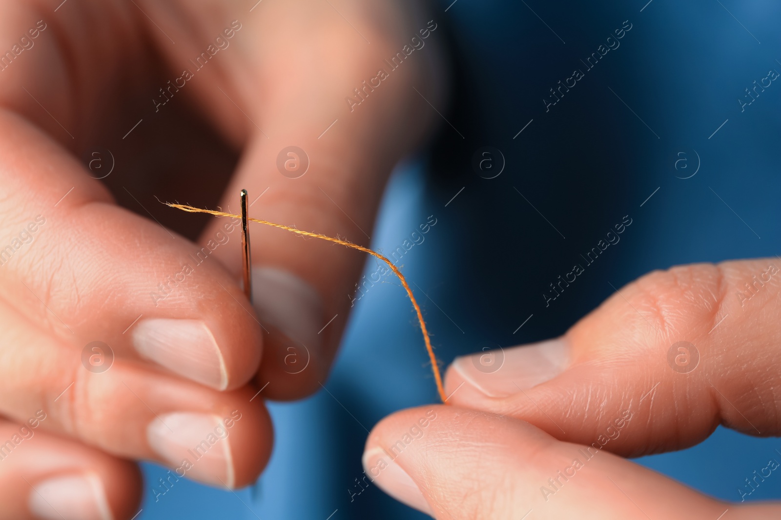 Photo of Closeup view of woman threading sewing needle