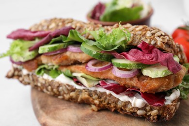 Photo of Delicious sandwich with schnitzel on wooden board, closeup