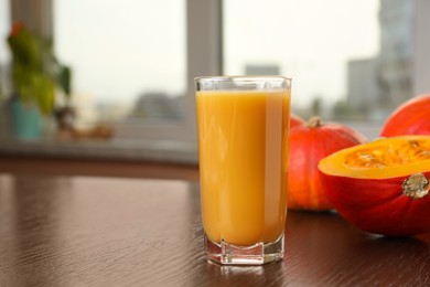 Photo of Tasty pumpkin juice in glass on wooden table indoors. Space for text