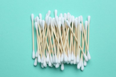 Heap of cotton buds on turquoise background, top view