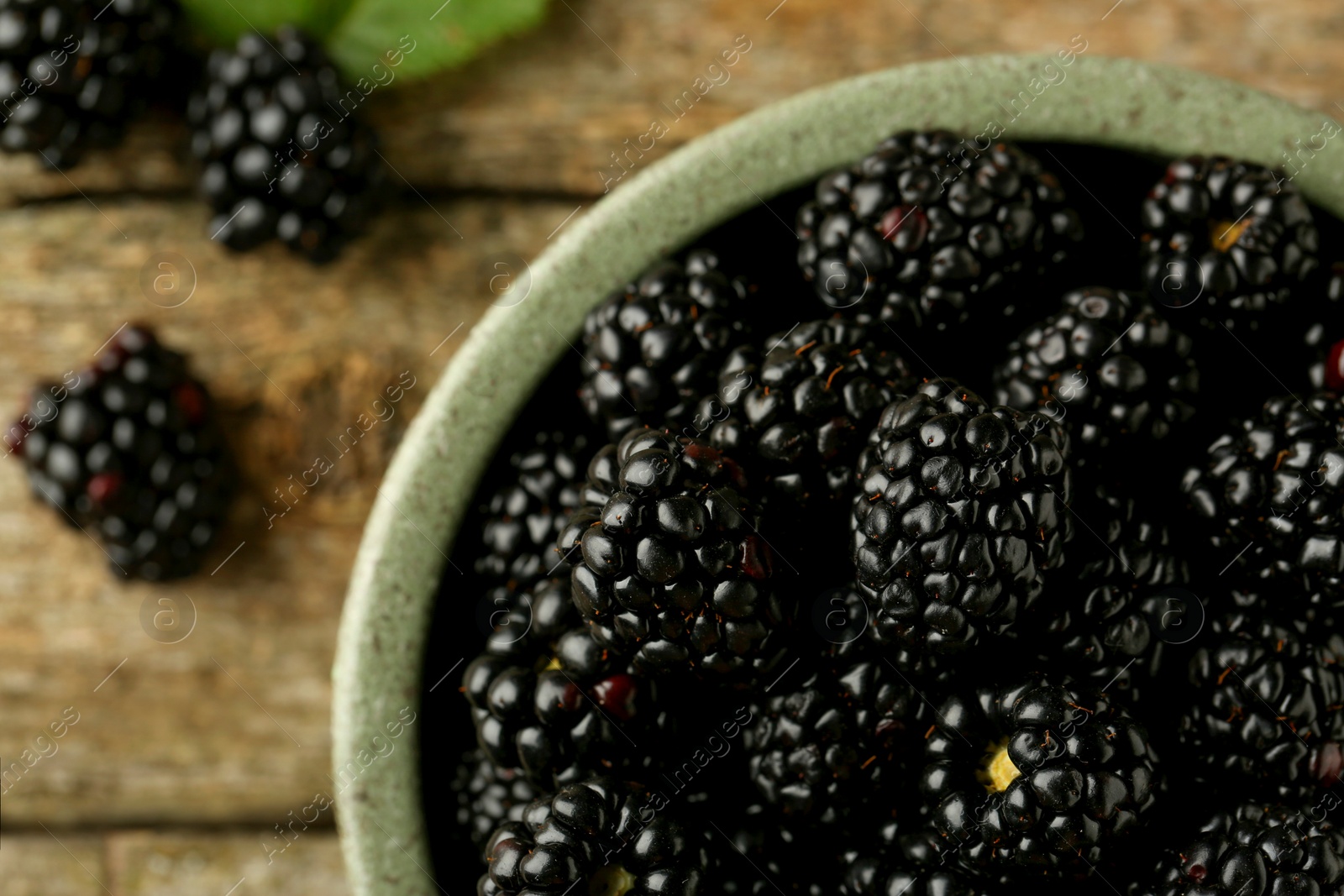 Photo of Bowl with fresh ripe blackberries on wooden table, top view