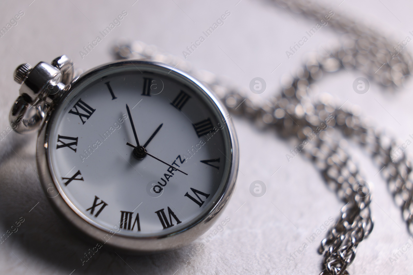 Photo of Silver pocket clock with chain on light table, closeup