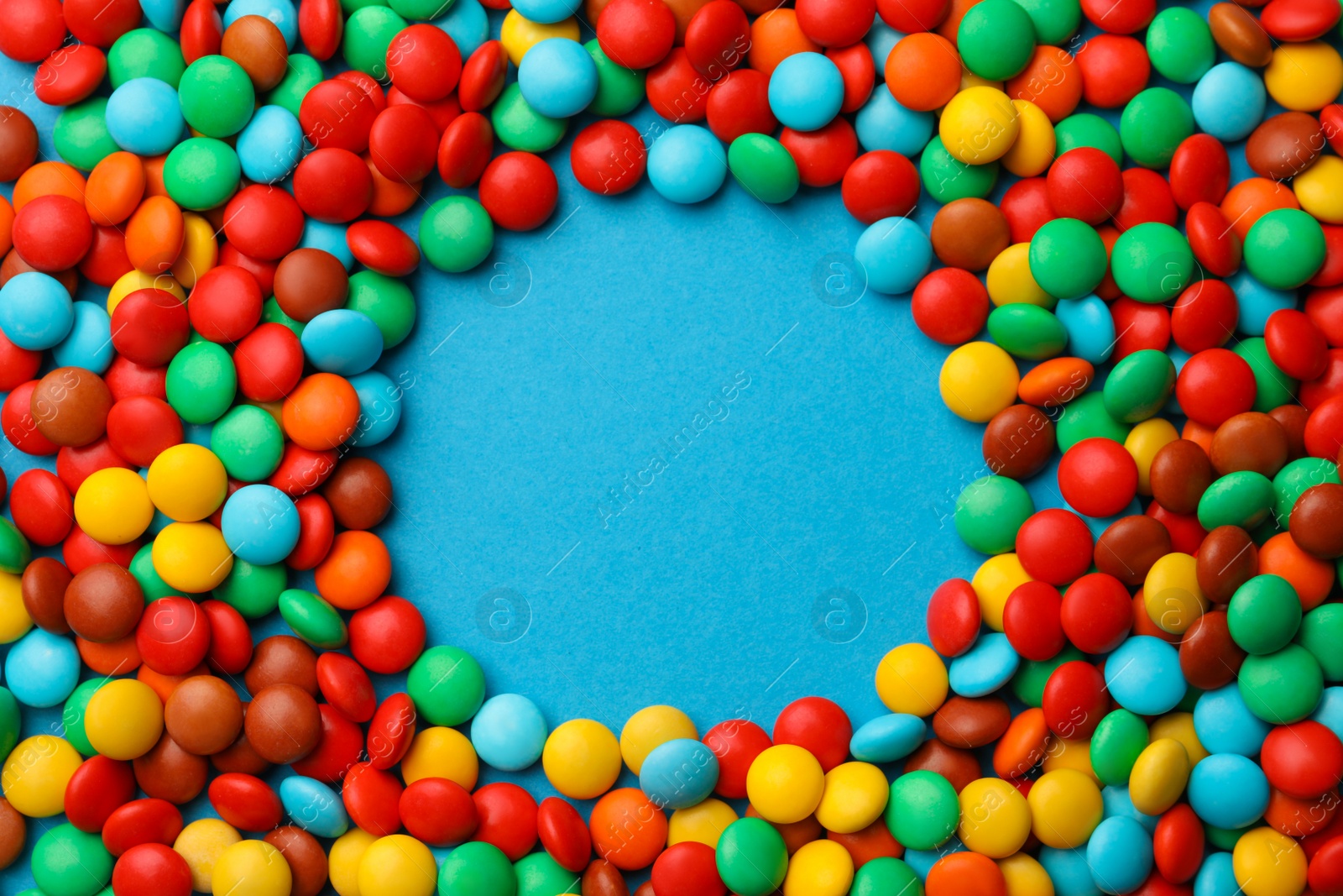 Photo of Frame of tasty colorful candies on blue background, flat lay. Space for text