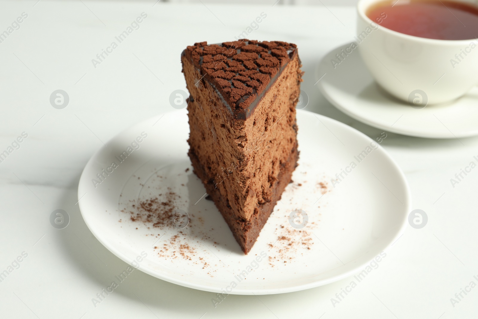 Photo of Piece of delicious chocolate truffle cake on white marble table, closeup