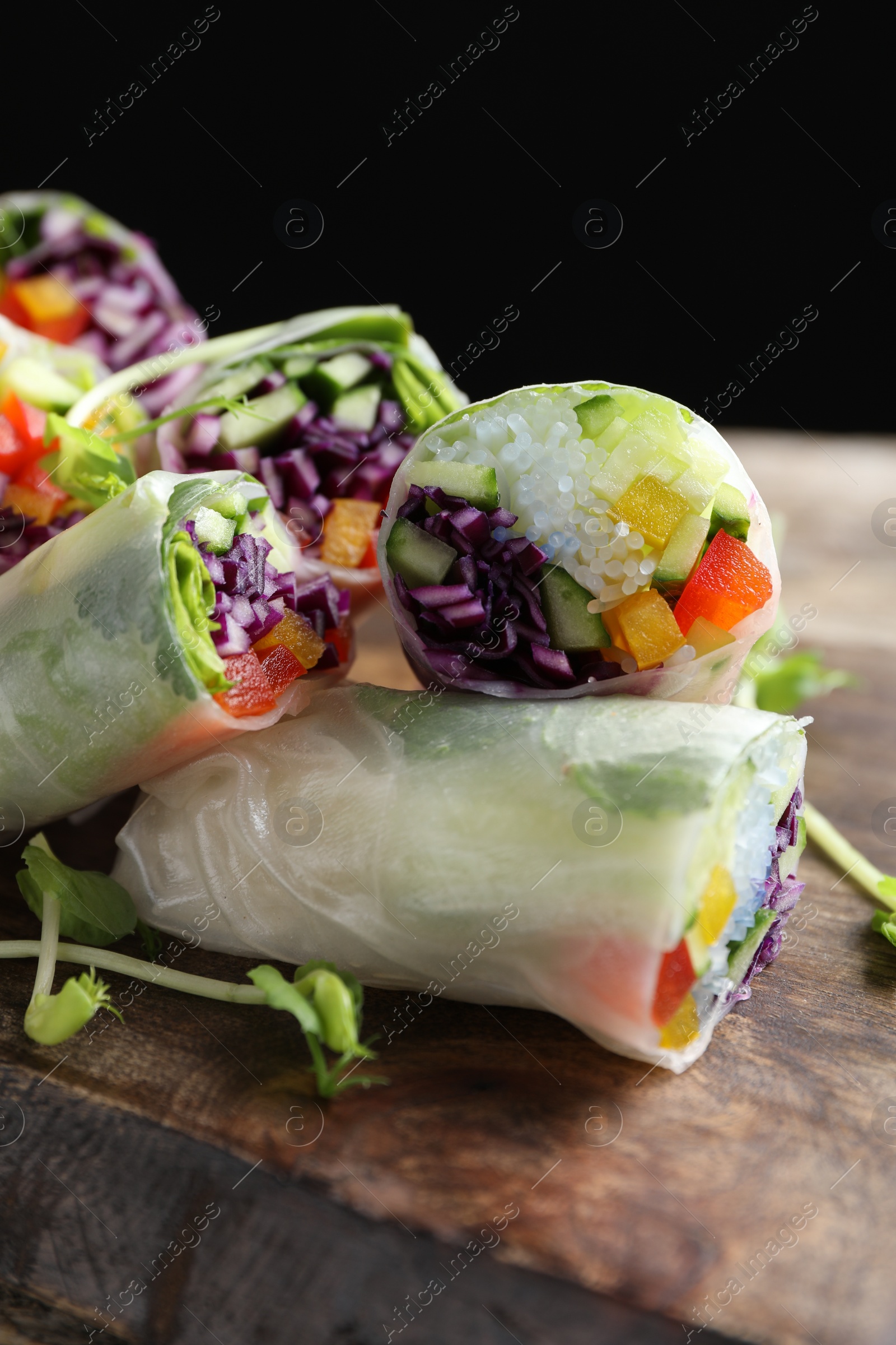 Photo of Delicious spring rolls wrapped in rice paper on wooden board, closeup