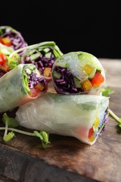 Photo of Delicious spring rolls wrapped in rice paper on wooden board, closeup