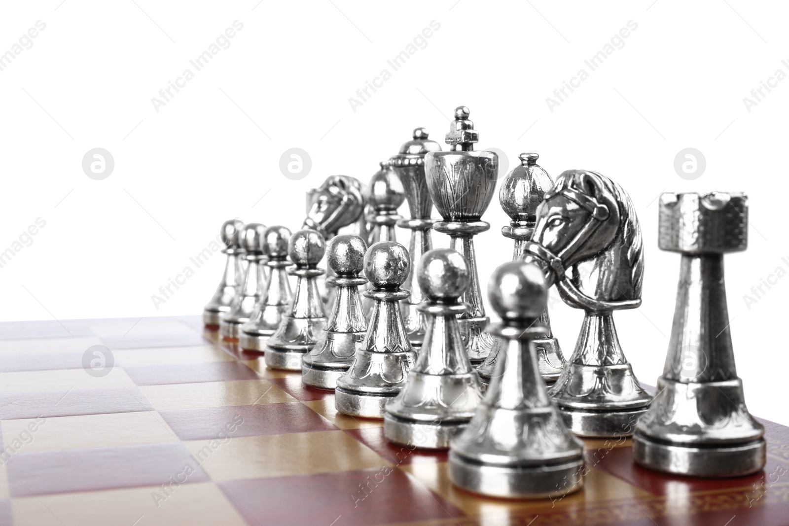 Photo of Set of silver chess pieces on wooden board against white background