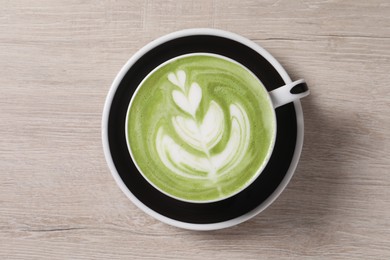 Cup of fresh matcha latte on wooden table, top view