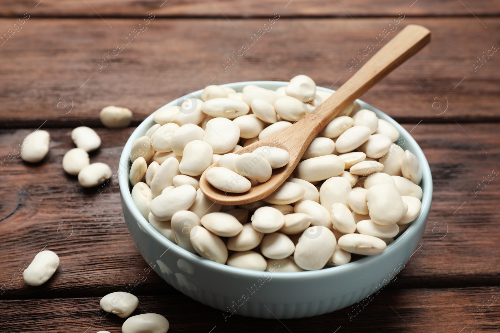 Photo of Raw white beans on wooden table, closeup