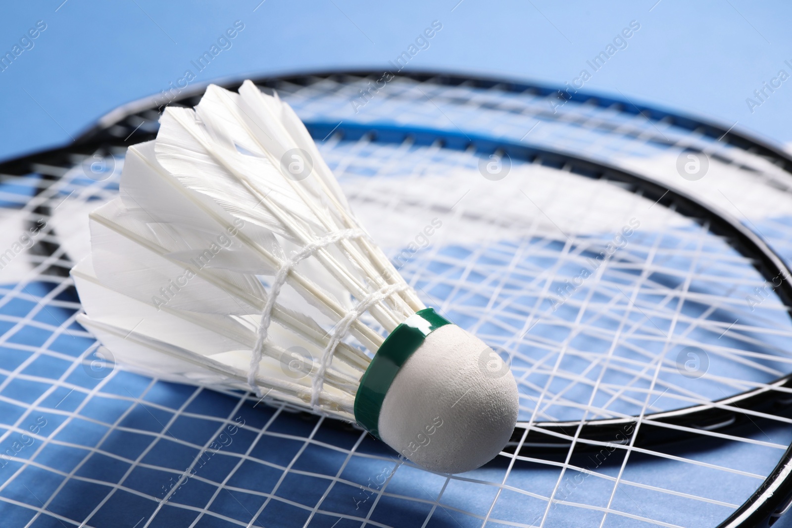 Photo of Feather badminton shuttlecock and rackets on blue background, closeup