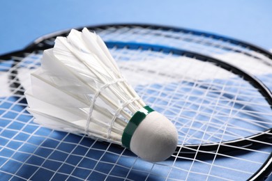 Feather badminton shuttlecock and rackets on blue background, closeup