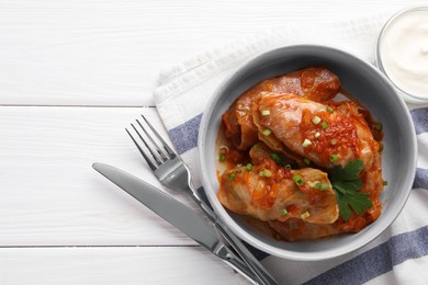 Photo of Delicious stuffed cabbage rolls cooked with homemade tomato sauce on white wooden table, flat lay. Space for text