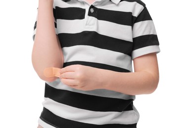 Photo of Little boy putting sticking plaster onto elbow on white background, closeup