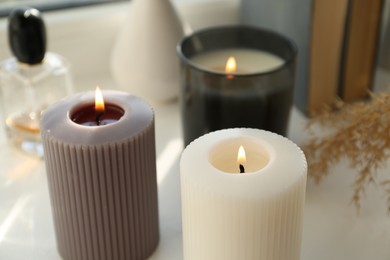 Different burning candles on white table. Decoration element