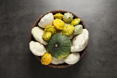 Photo of Fresh ripe pattypan squashes in wicker bowl on grey table, top view