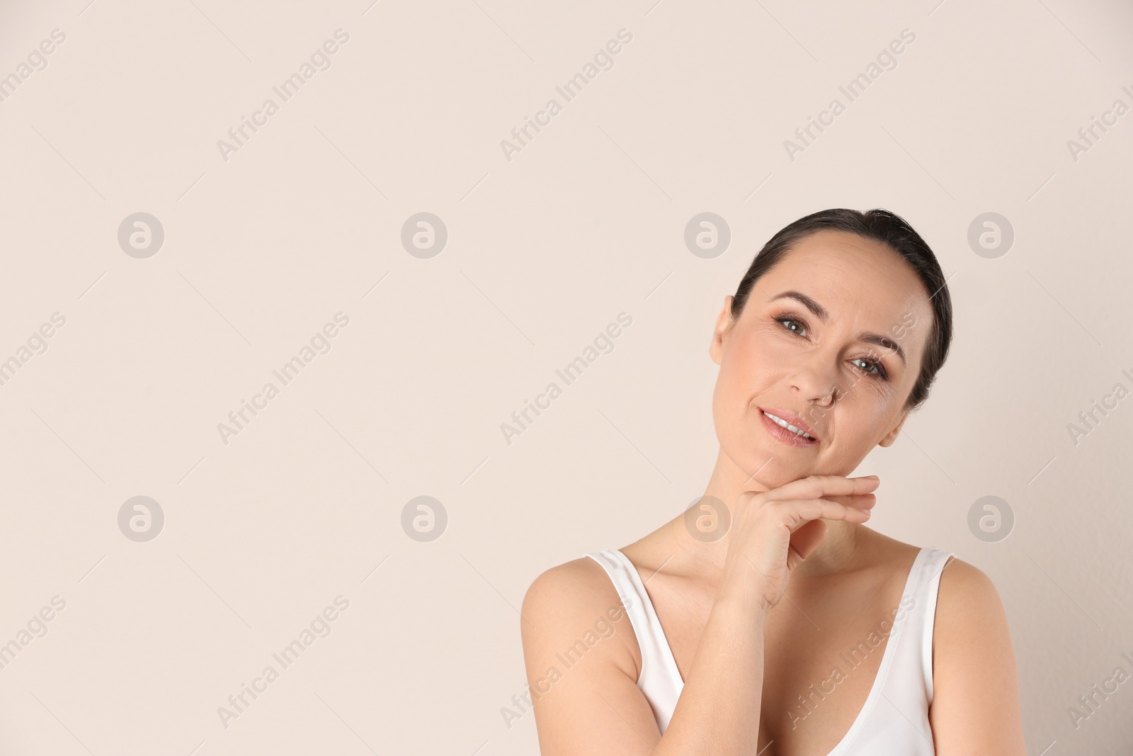 Photo of Portrait of beautiful mature woman on beige background. Space for text