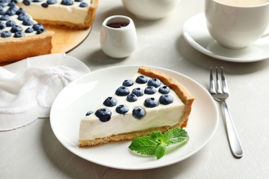 Plate with piece of tasty blueberry cake on gray table