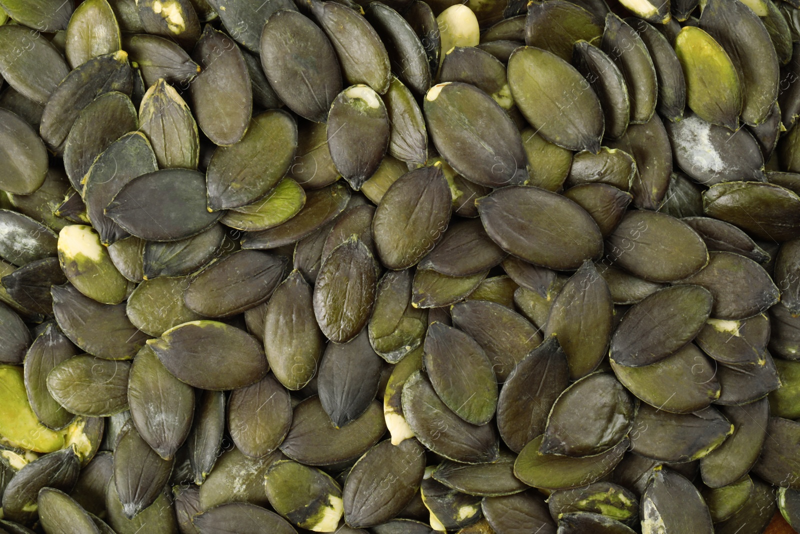 Photo of Many peeled pumpkin seeds as background, top view