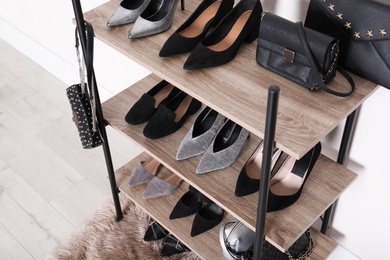 Shelving unit with stylish shoes and purses near white wall. Element of dressing room interior