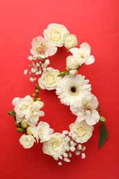 Photo of Number 8 made of beautiful white flowers on red background, flat lay. International Women's day