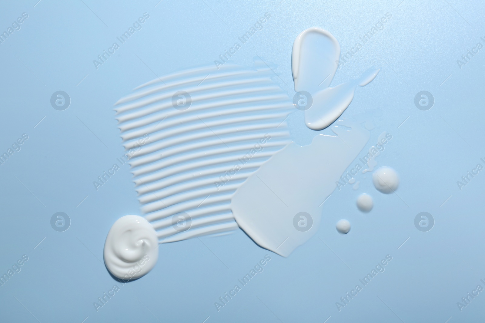 Photo of Samples of face cream on light blue background, top view