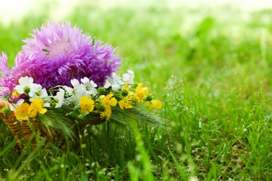 Photo of Bouquet of beautiful wildflowers on green grass outdoors, closeup. Space for text