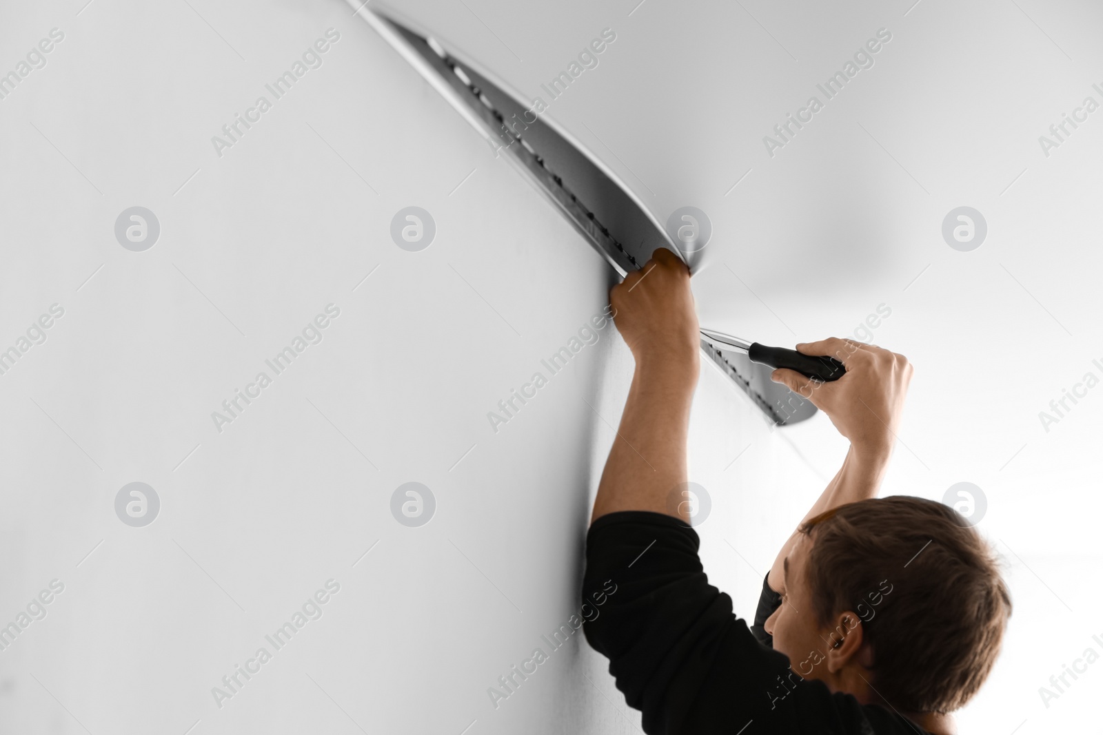 Photo of Repairman installing white stretch ceiling in room