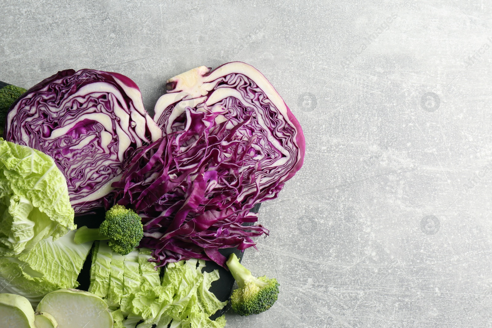 Photo of Different types of cut cabbage on light grey table, flat lay. Space for text