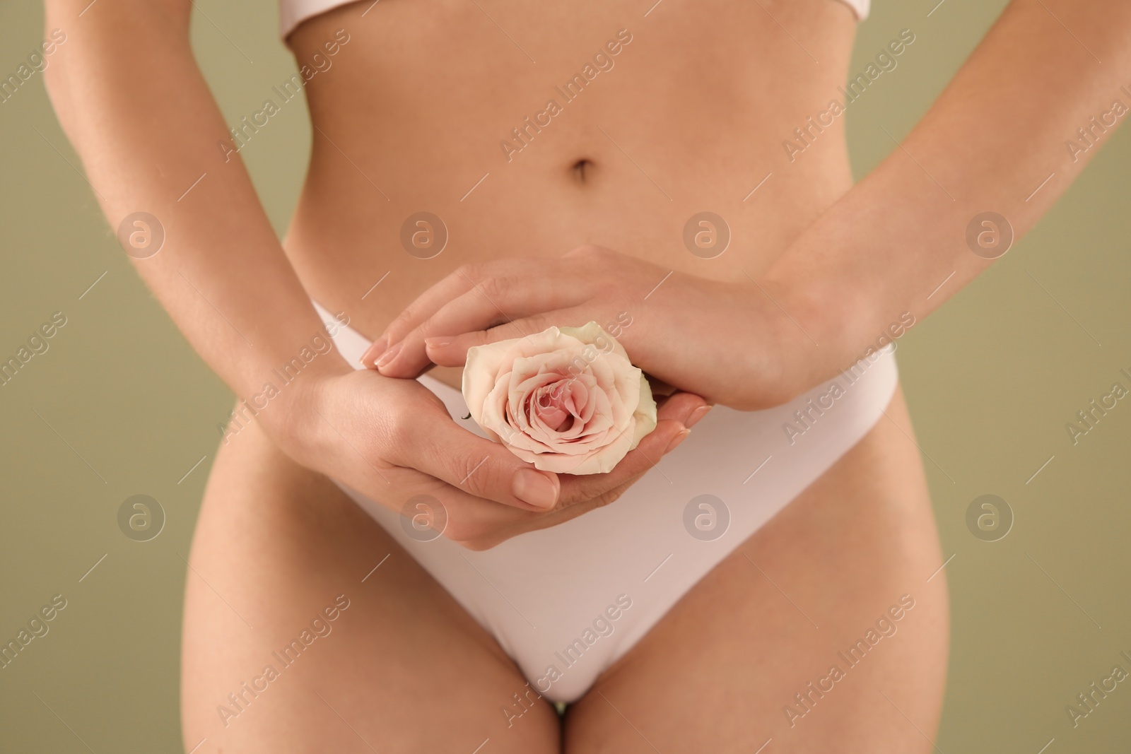 Photo of Gynecology. Woman in underwear with rose flower on green background, closeup